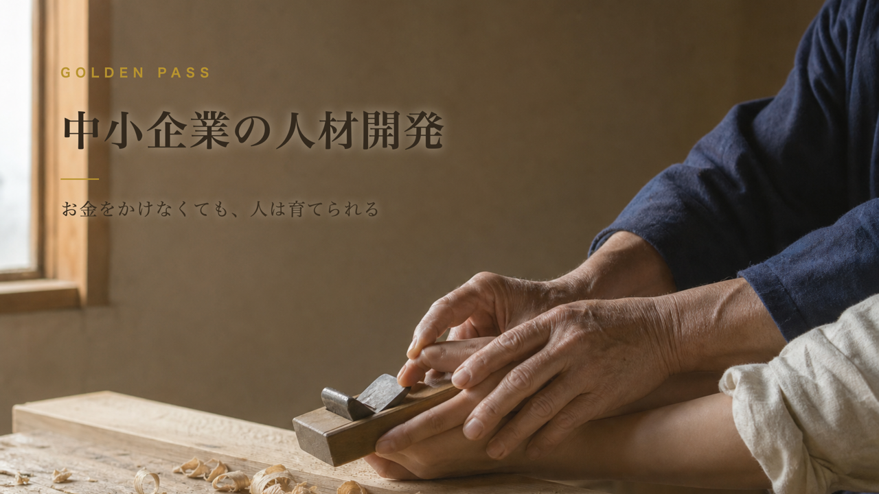木工の工房で、年配の職人の手が若手の手に鉋の使い方を教えている手元。記事タイトル「中小企業の人材開発」